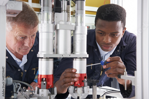 Valokuva Engineer And Apprentice Working On Machine In Factory