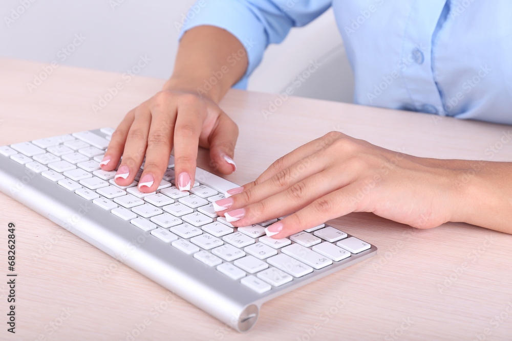 Female hands typing on keyboard, close-up, on light background Female hands typing on keyboard, close-up, on light background