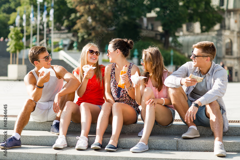 group of smiling friends sitting on city square group of smiling friends sitting on city square