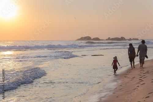 Family walking on sandy beach at sunset