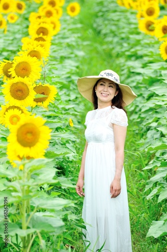 ひまわり畑に立っている白いワンピースと麦わら帽子を着ているアジア人の美しい女性 Stock Foto Adobe Stock