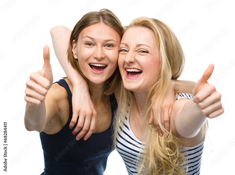 Two young happy women showing thumb up sign