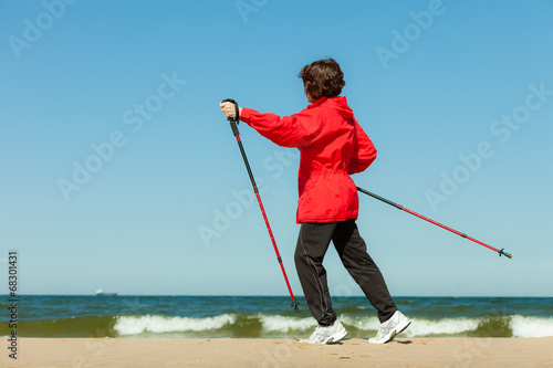 Nordic walking. Woman hiking on the beach.