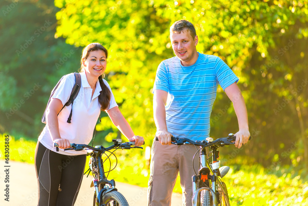 Obraz premium young couple on the weekend to ride a bike in the park