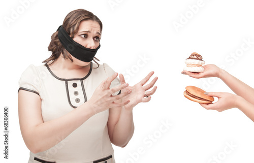 Plus size woman gagged stretching hands to junk food photo