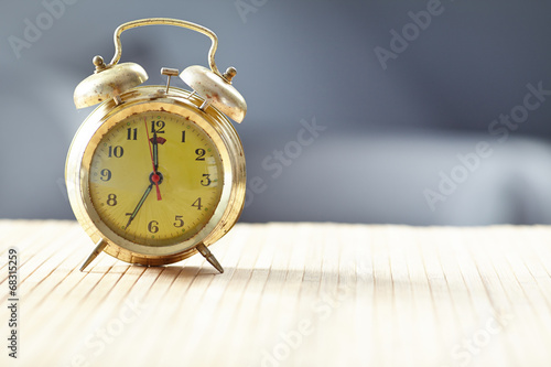 Retro alarm clock on desk front grey wall background