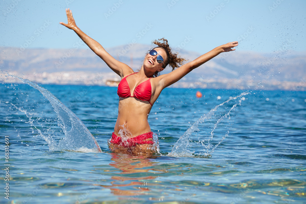 Beautiful bikini model splashing water