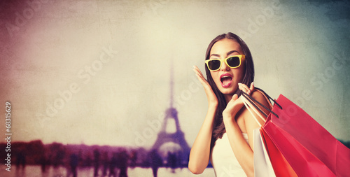 Canvas Print Brunette girl with shopping bags on Parisian background.