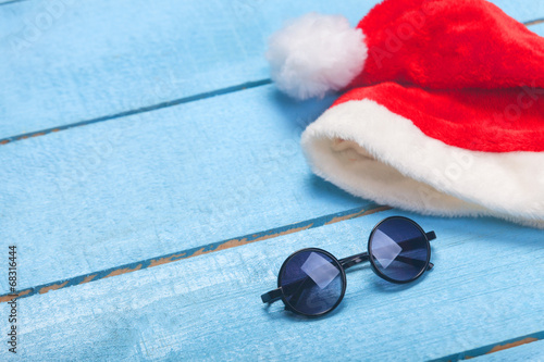 Sunglasses and christmas hat on blue wood