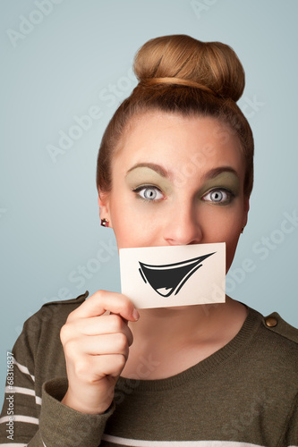 Happy cute girl holding paper with funny smiley drawing