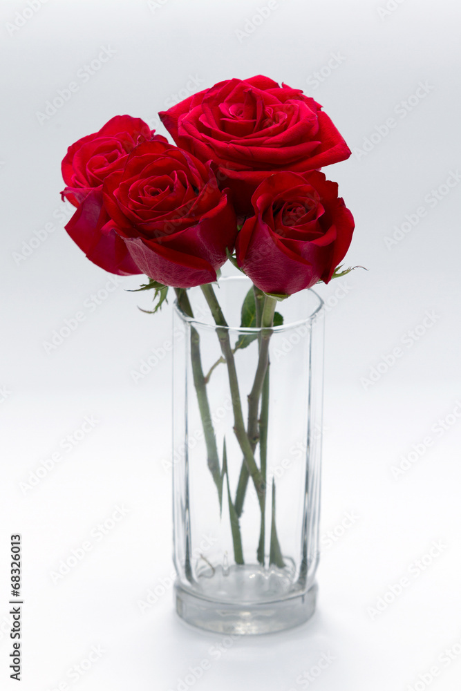 Cementerio Masaje Adaptado Cuatro rosas rojas dentro de vaso de cristal sobre una mesa roja foto de  Stock | Adobe Stock