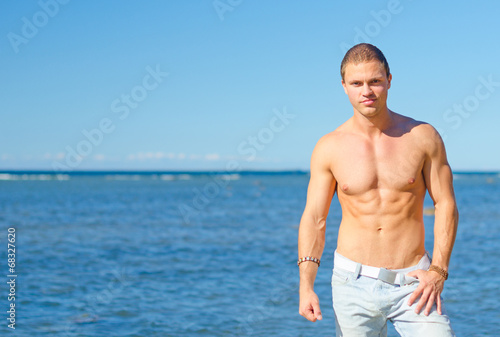 Muscular attractive man posing near the sea.