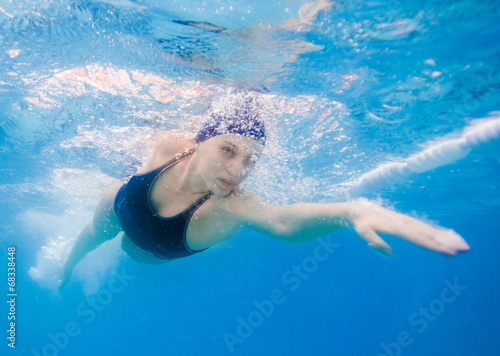Young woman swimming the front crawl in a pool, taken underwater
