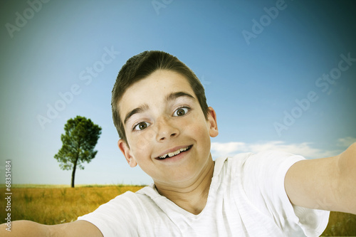 Fototapeta Young boy with phone becoming a self-portrait