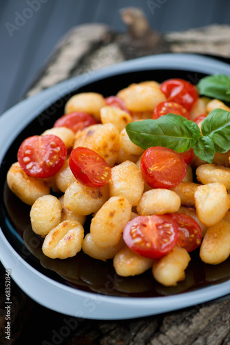 Fried italian gnocchi with red cherry tomatoes on a glass plate