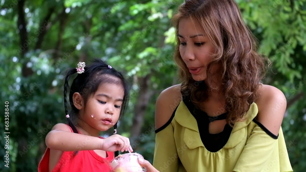 An asian girl is eating delicious cupcake with mother. An asian girl is eating delicious cupcake with mother.