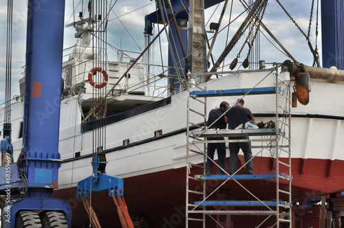 Operai riparano peschereccio in cantiere navale