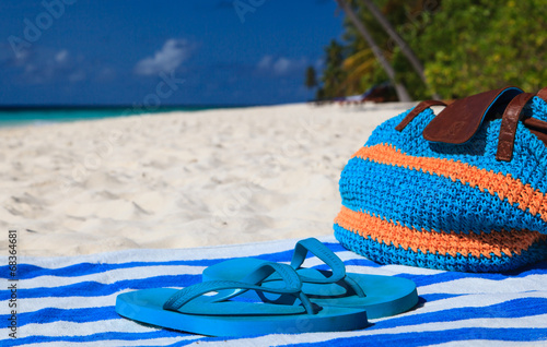 Straw bag, towel and flip flops on a tropical beach