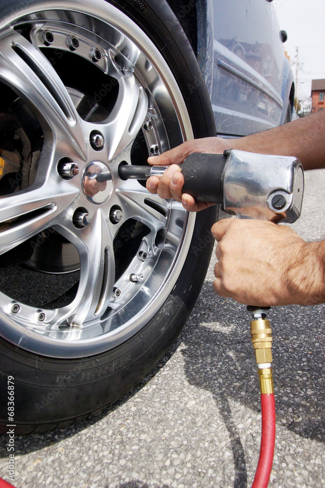 Fototapeta premium Auto mechanic changing car wheel