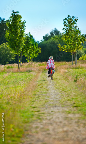 boy is riding  bike on a park road © Margarita Borodina