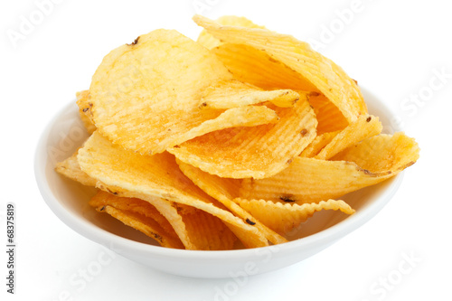 Crinkle cut crisps in a white bowl on white background.