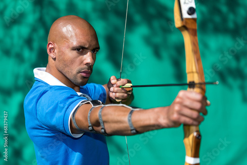 Canvas Print Archer aiming at target with bow and arrow