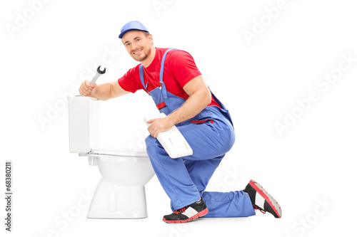 Smiling plumber trying to fix a toilet