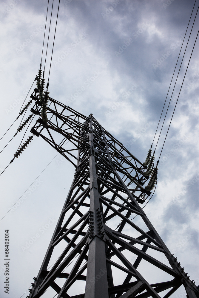 Electricity pylon against the cloudy sky background