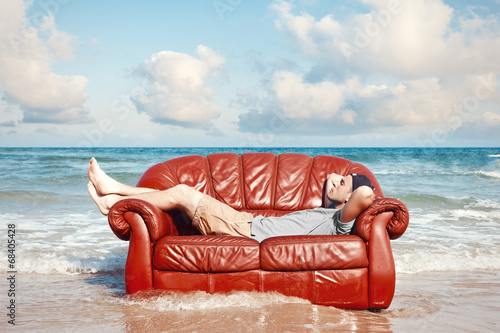 man resting in leather couch on the beach