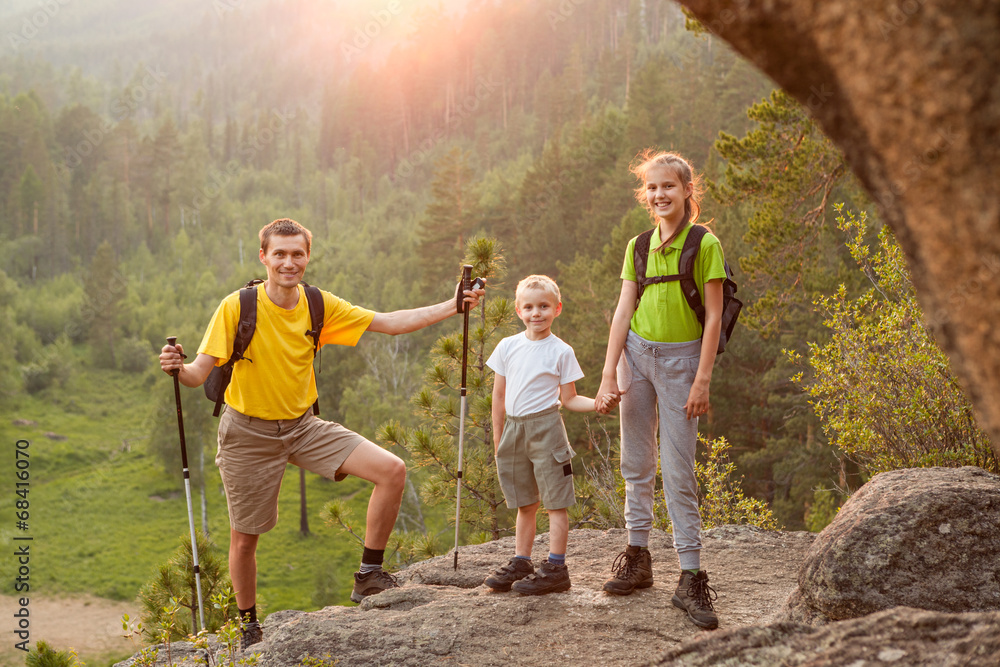 Obraz premium Father and two children with backpacks on beautiful nature