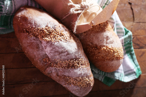 Fresh baked bread wrapped in paper, on wooden background