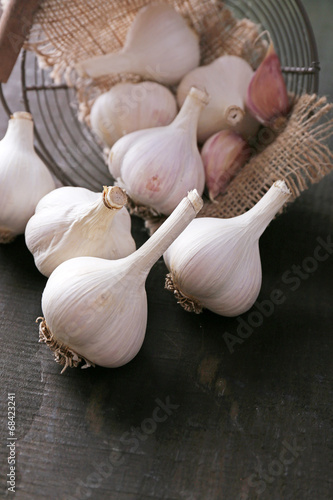 Garlic in basket on black wooden background