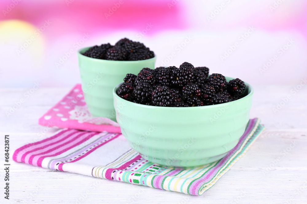 Sweet blackberries in color bowl on bright background Sweet blackberries in color bowl on bright background