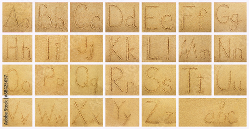 Handwritten alphabet letters on sand background photo