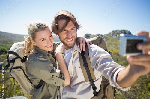 Hiking couple standing on mountain terrain taking a selfie © WavebreakMediaMicro