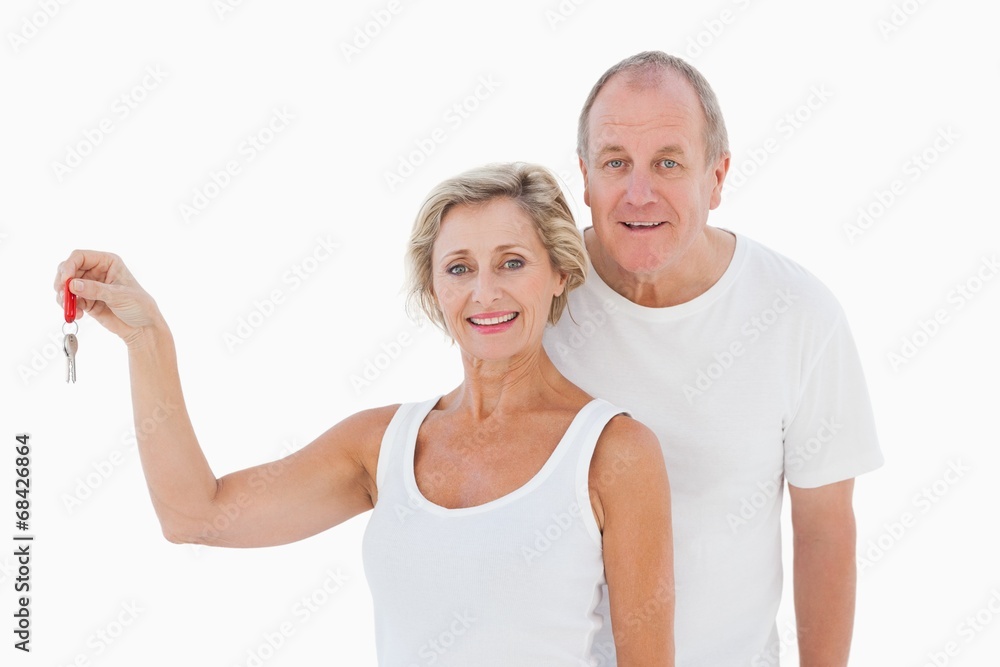 Mature couple smiling at camera with new house key Mature couple smiling at camera with new house key