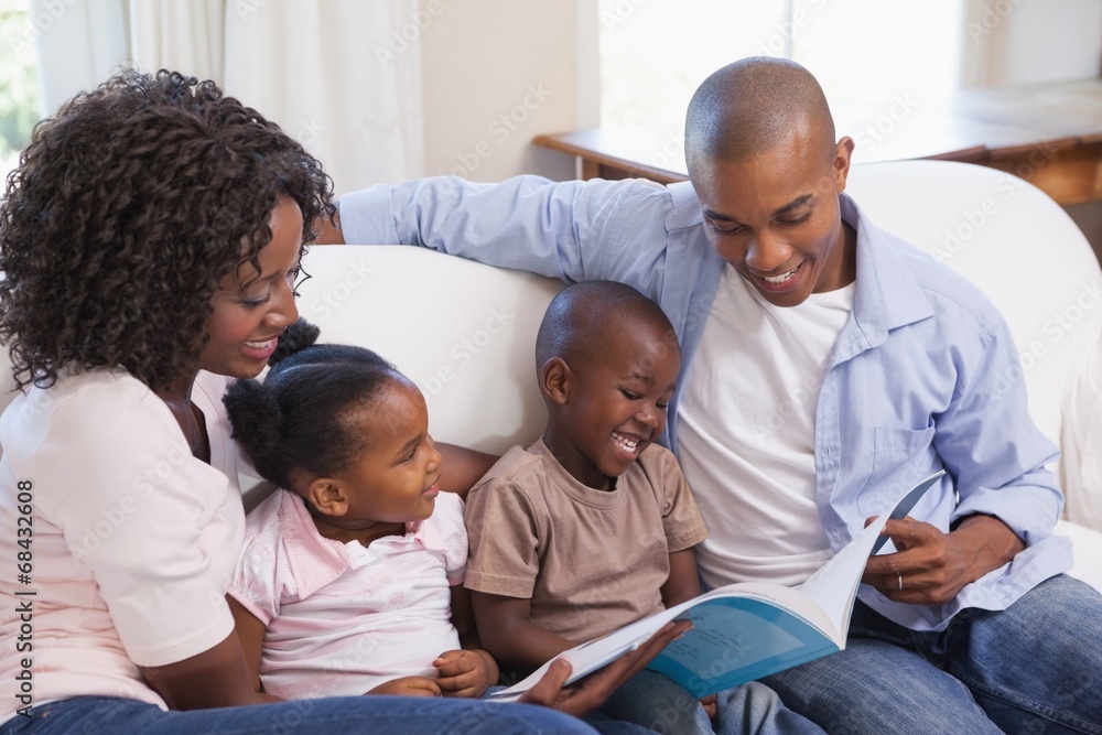 Happy family sitting on couch together reading book Happy family sitting on couch together reading book