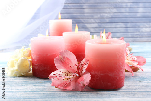 Beautiful candles with flowers on wooden background