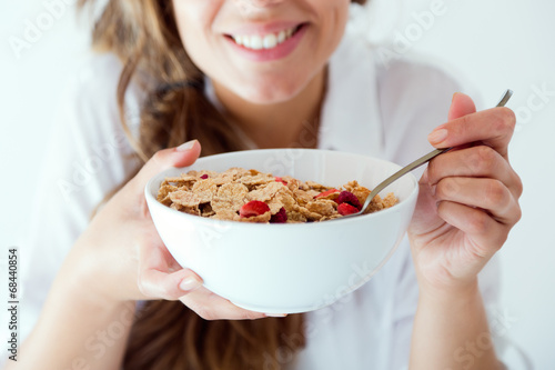 Young woman in underwear eating cereals. Isolated on white.