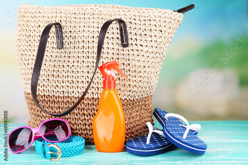 Summer wicker bag with accessories on nature background