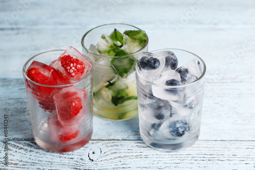 Ice cubes with mint leaves, raspberry and blueberry in glasses,