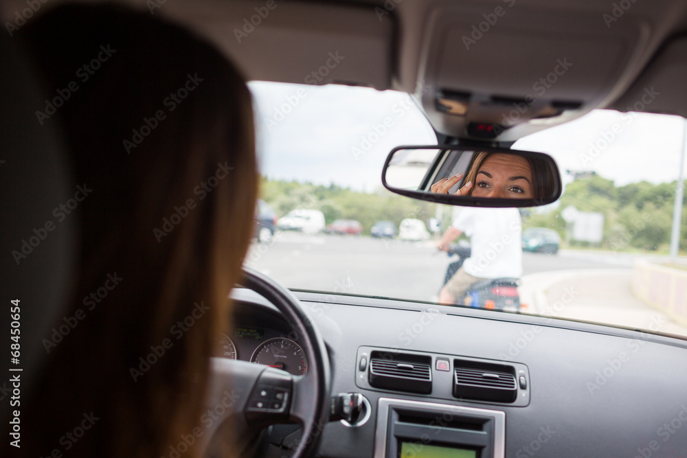 Fototapeta premium Young, woman driving a car, going home from work, fixing her mak