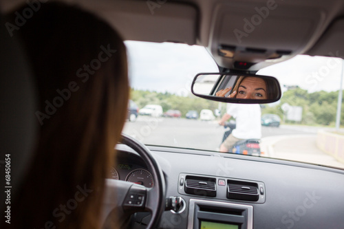 Young, woman driving a car, going home from work, fixing her mak © lightpoet