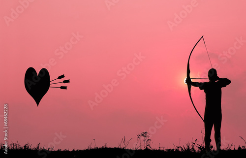 Silhouette archery shoots a bow at the heart shape target in the