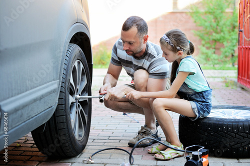 Cute  girl helps her father to change wheel  photo