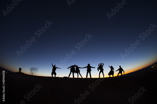 Group of happy people on top of a mountain in the Sahara desert 