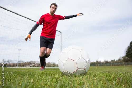 Goalkeeper in red kicking ball away from goal © WavebreakMediaMicro