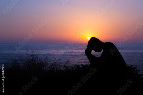 Obraz na plátně Man Praying by the Sea at Sunset