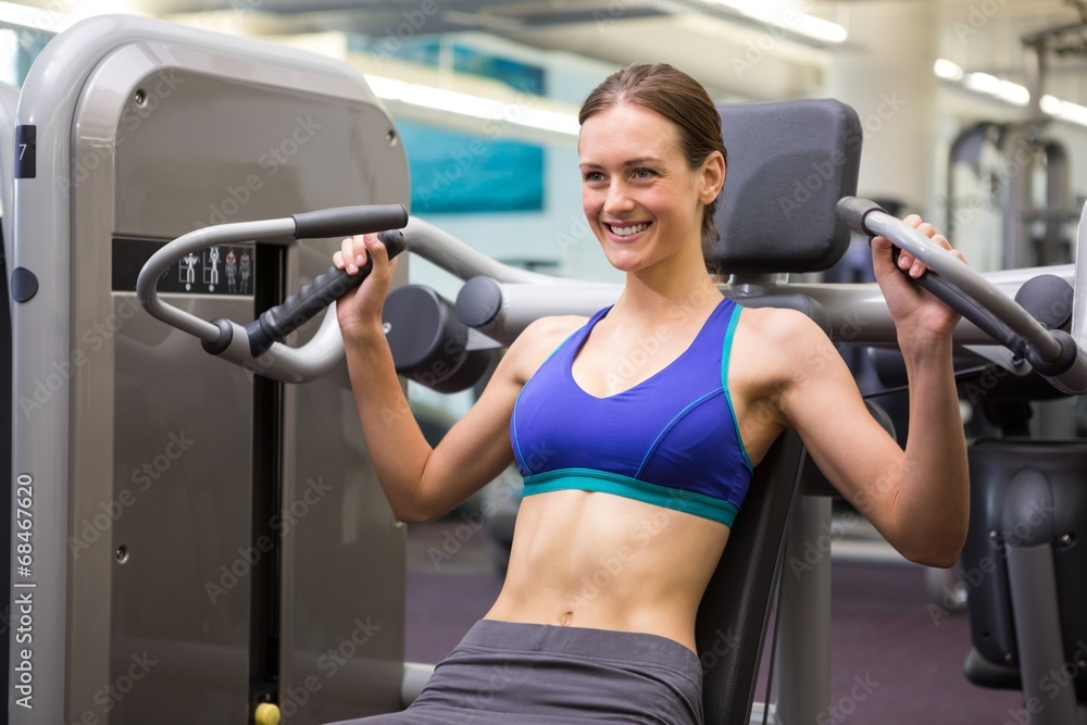 Fit smiling brunette using weights machine for arms Fit smiling brunette using weights machine for arms