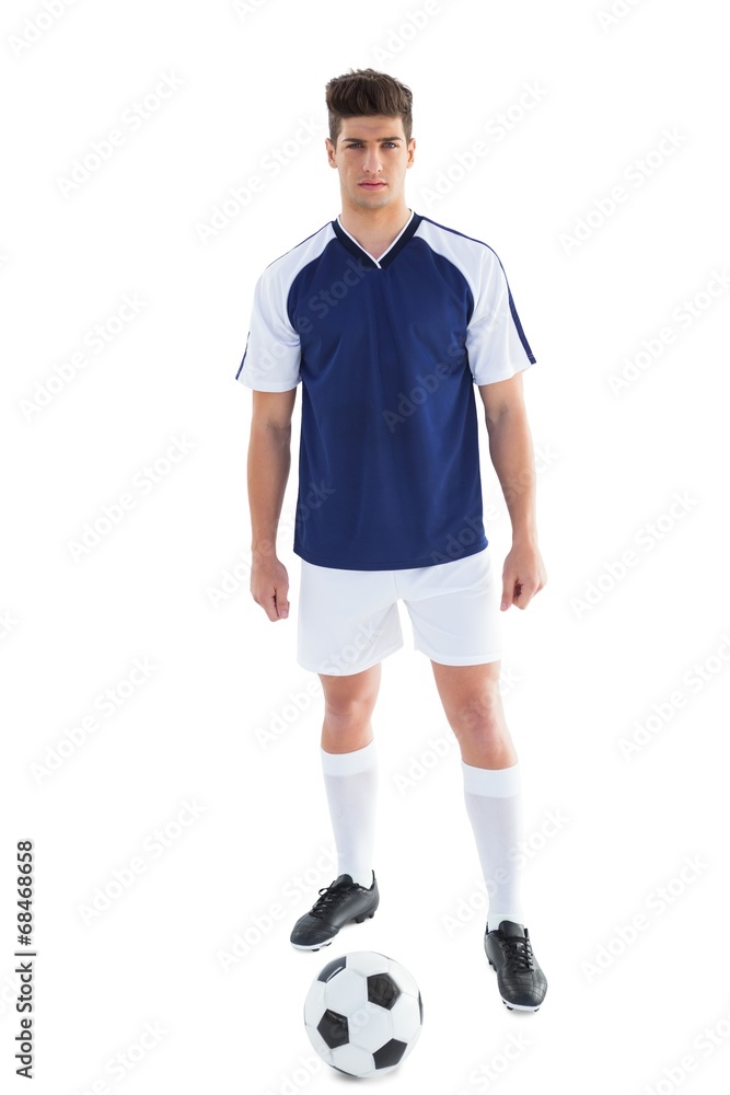Football player in blue standing with the ball Football player in blue standing with the ball